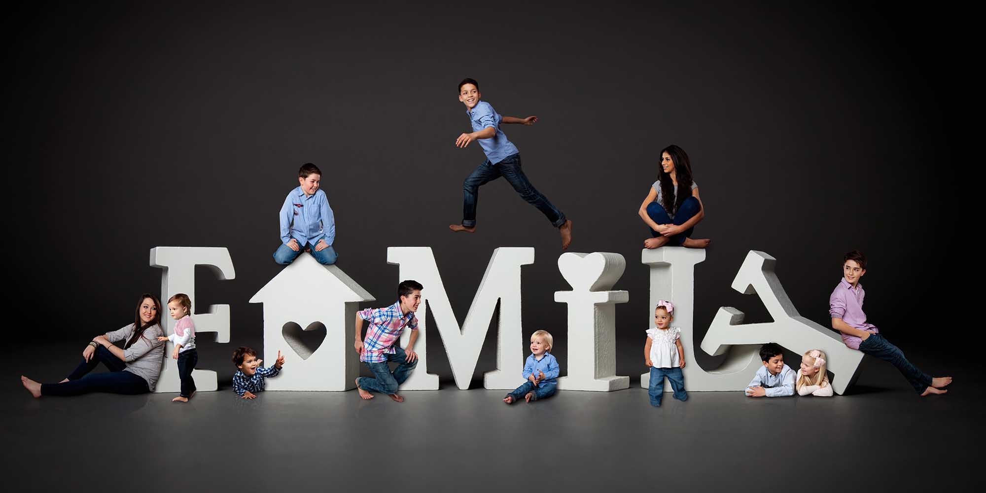 Creative Family Portrait with Children jumping and gathering around large letters that spell family.
